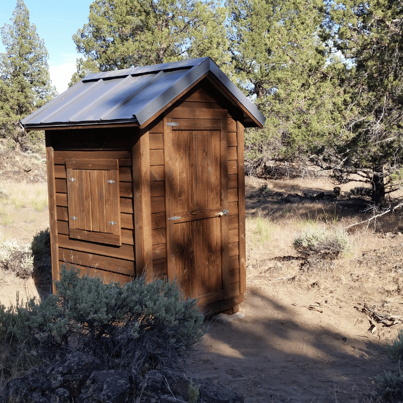 DIY Oregon Timber Werks outhouse kit set in the woods, showcasing rustic design, craftsmanship, and eco-friendly features suitable for homesteading