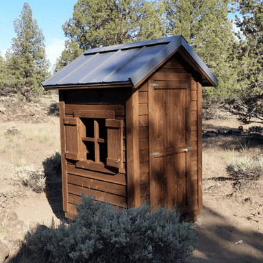 Oregon Timber Werks handmade rustic wooden outhouse cabin nestled in the forest with an open window, showcasing the natural surroundings and eco-friendly craftsmanship
