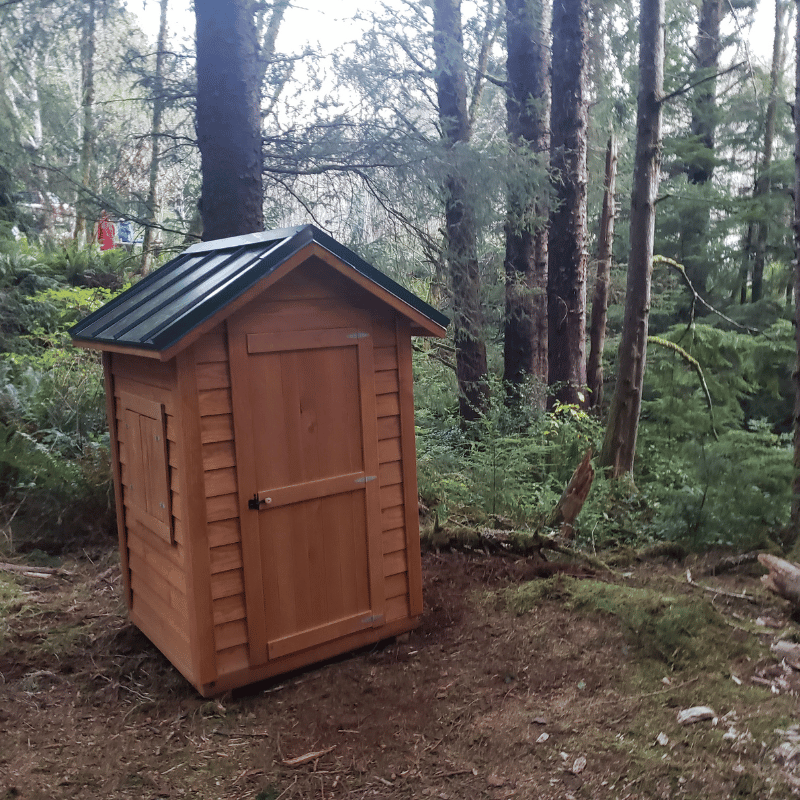Front and side view of the DIY Oregon Timber Werks outhouse kit, highlighting the rustic design, craftsmanship, eco-friendly features, and suitability for homesteading